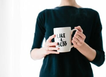 woman holding white mug while standing